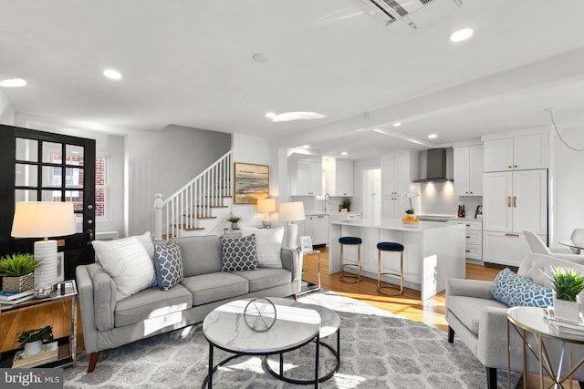 living room with light wood-type flooring, visible vents, recessed lighting, and stairs