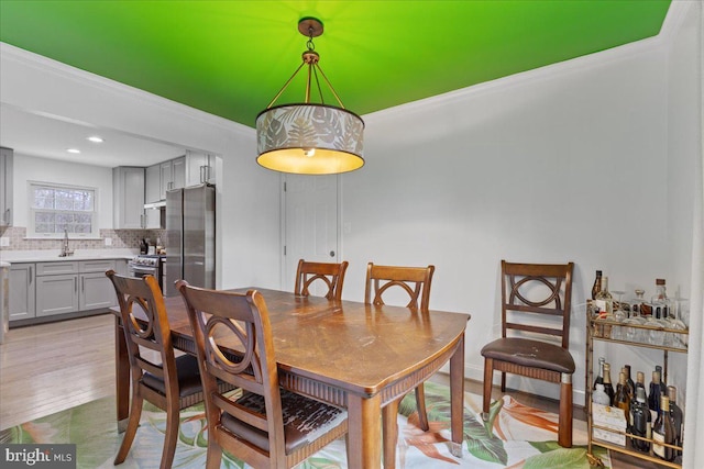 dining area with light wood-style floors, recessed lighting, and crown molding