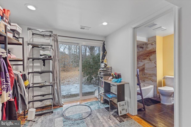 interior space featuring visible vents, shower / washtub combination, wood finished floors, and toilet