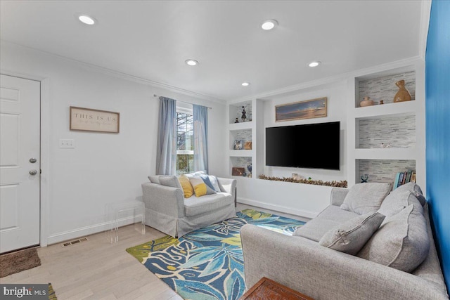 living room featuring built in features, crown molding, light wood finished floors, visible vents, and baseboards