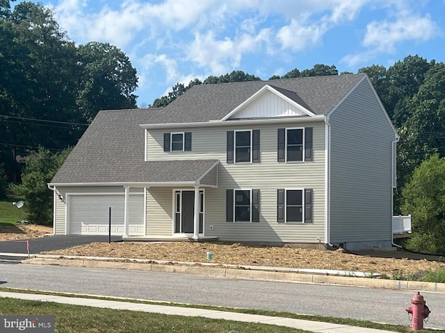 view of front of property with driveway, an attached garage, and roof with shingles