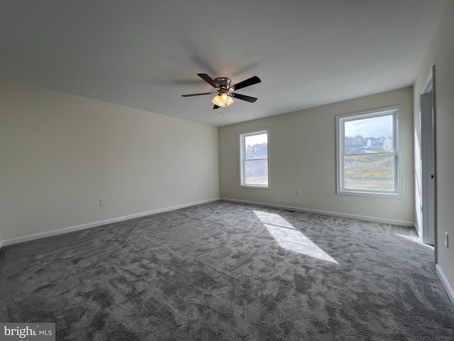 empty room with ceiling fan, dark colored carpet, and baseboards