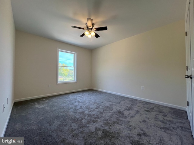 empty room featuring ceiling fan, dark carpet, and baseboards