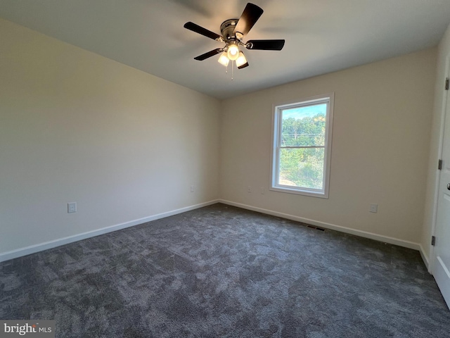 spare room featuring baseboards, visible vents, dark colored carpet, and a ceiling fan