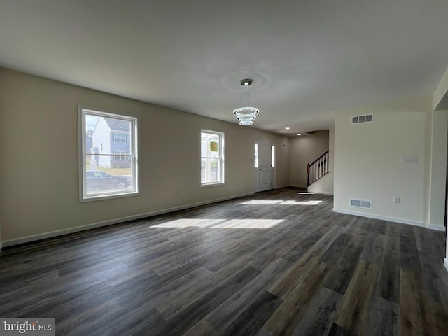 unfurnished living room featuring stairway, dark wood-style flooring, and visible vents