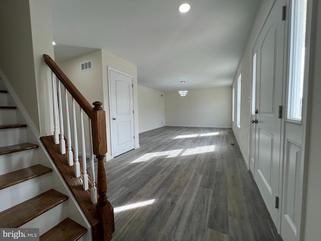 foyer with baseboards, visible vents, dark wood-style floors, stairway, and a wealth of natural light