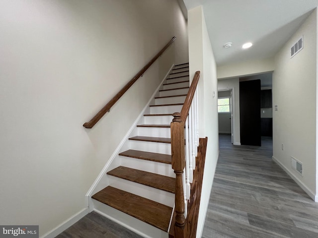 stairway with baseboards, visible vents, and wood finished floors