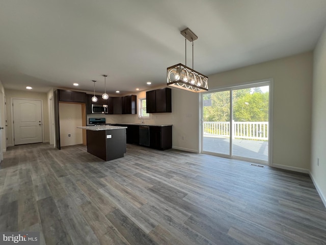 kitchen with a sink, wood finished floors, a kitchen island, open floor plan, and appliances with stainless steel finishes