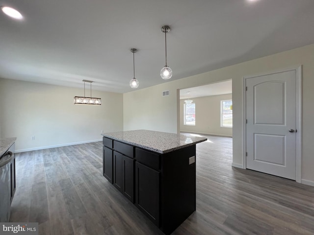 kitchen featuring a kitchen island, light stone counters, open floor plan, dark wood-type flooring, and pendant lighting