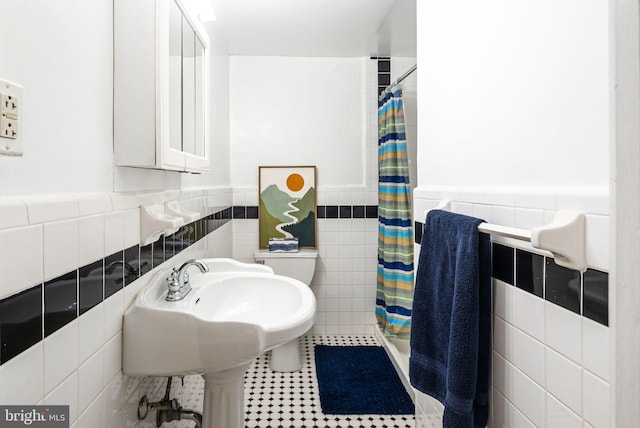 bathroom featuring tile patterned flooring, toilet, tile walls, wainscoting, and a shower stall