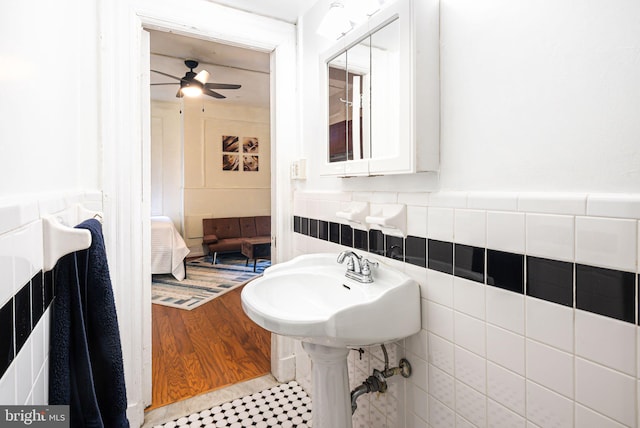 ensuite bathroom featuring a wainscoted wall, a ceiling fan, tile walls, and ensuite bathroom