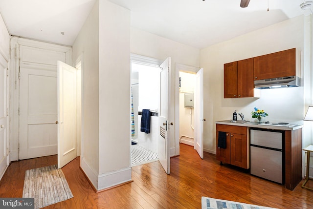 kitchen featuring dark wood-style floors, light countertops, brown cabinets, and under cabinet range hood