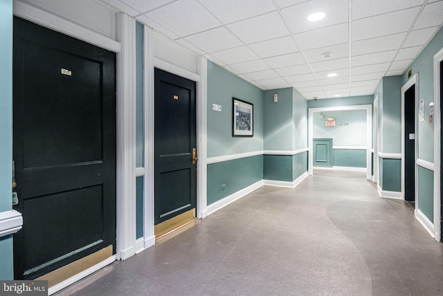 hallway featuring recessed lighting, a drop ceiling, finished concrete floors, and baseboards