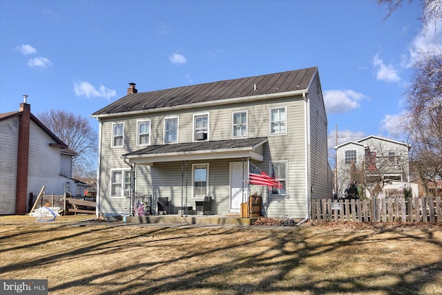 rear view of property featuring a standing seam roof, a porch, fence, metal roof, and a chimney