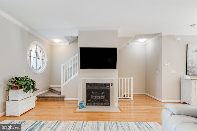 unfurnished living room featuring crown molding, a fireplace with flush hearth, wood finished floors, baseboards, and stairs