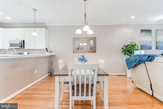 dining area featuring light wood finished floors, ornamental molding, and baseboards