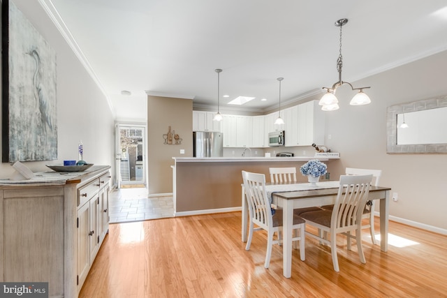 dining area featuring crown molding, light wood-style flooring, and baseboards