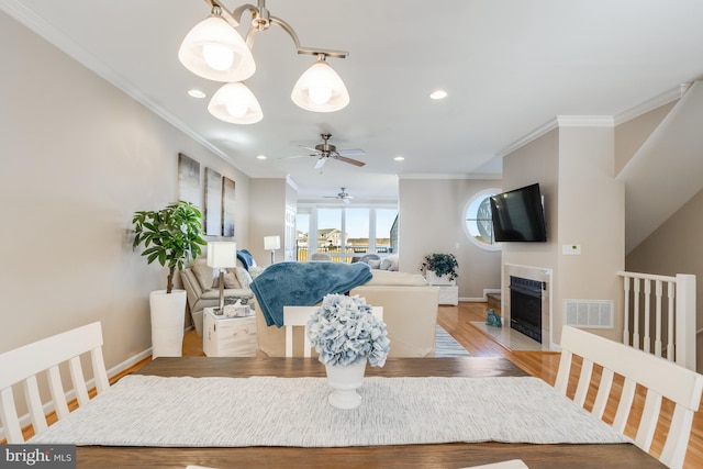 dining space featuring light wood-style flooring, visible vents, and ornamental molding