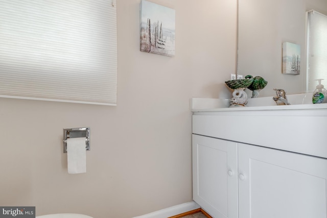 half bathroom with toilet, baseboards, and vanity