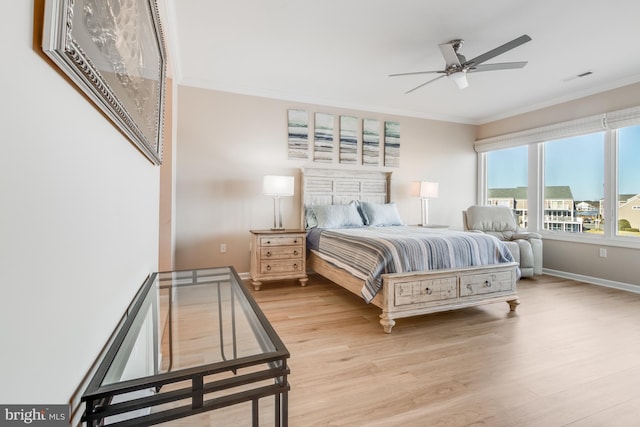 bedroom featuring baseboards, light wood-style flooring, visible vents, and crown molding