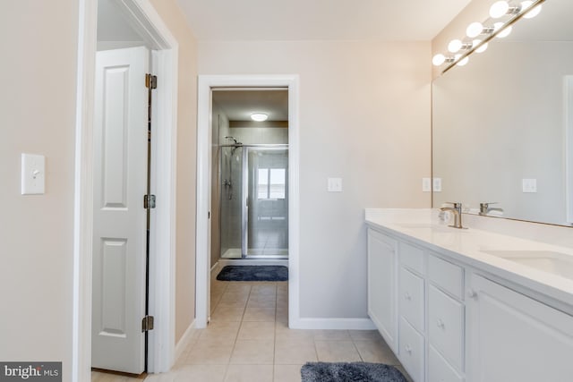 bathroom with double vanity, a stall shower, a sink, baseboards, and tile patterned floors