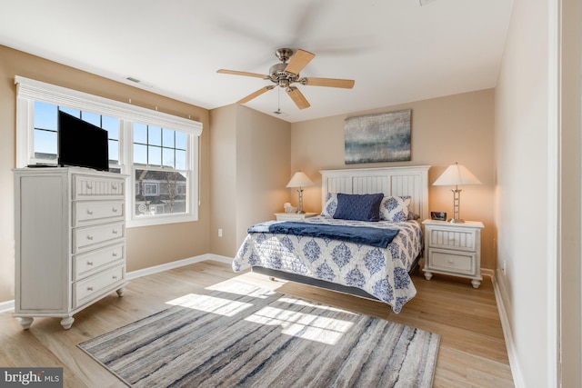 bedroom with ceiling fan, light wood-style flooring, and baseboards