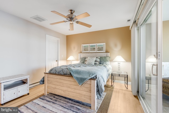 bedroom featuring visible vents, ceiling fan, baseboard heating, and wood finished floors