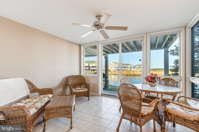 sunroom / solarium with a ceiling fan and a water view