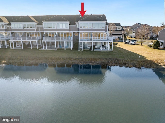 rear view of house featuring a lawn, a water view, and a residential view