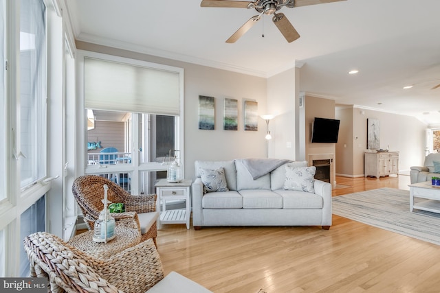 living room with light wood-style flooring, ceiling fan, and crown molding