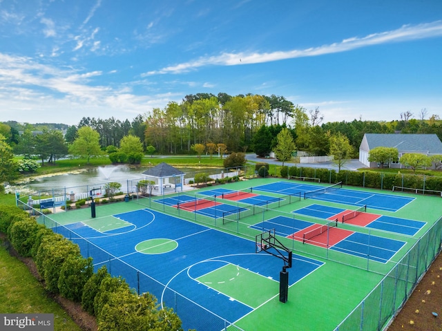 view of basketball court featuring a tennis court, a water view, and fence