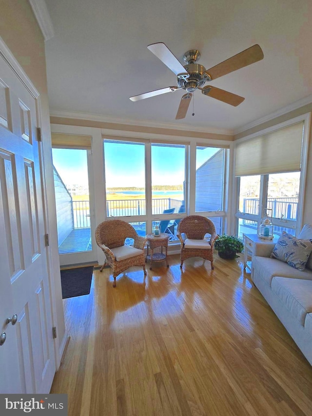 sunroom / solarium with a ceiling fan and a water view