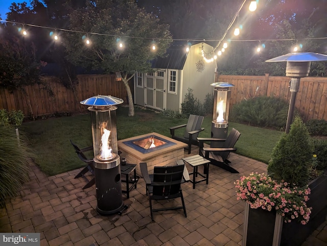 patio at twilight with a fire pit, a storage shed, an outdoor structure, and fence