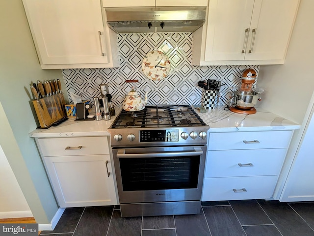 kitchen with white cabinets, light stone counters, under cabinet range hood, stainless steel range with gas cooktop, and backsplash