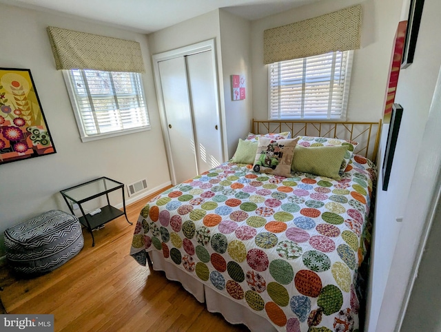 bedroom featuring a closet, multiple windows, wood finished floors, and visible vents