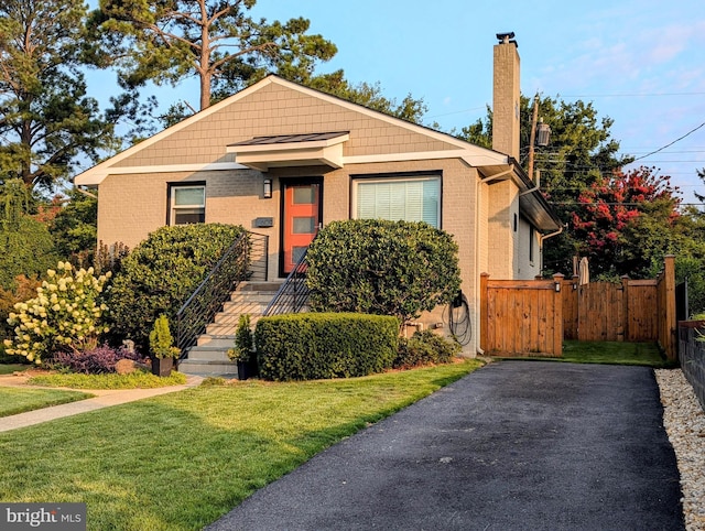 bungalow-style house with brick siding, a front lawn, and fence