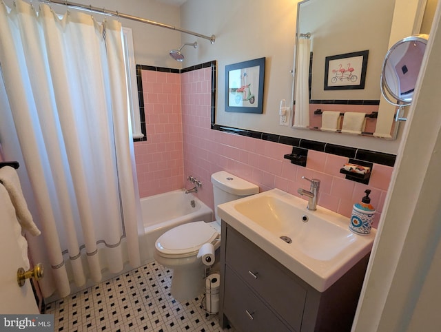 full bathroom featuring wainscoting, toilet, shower / bath combination with curtain, vanity, and tile walls