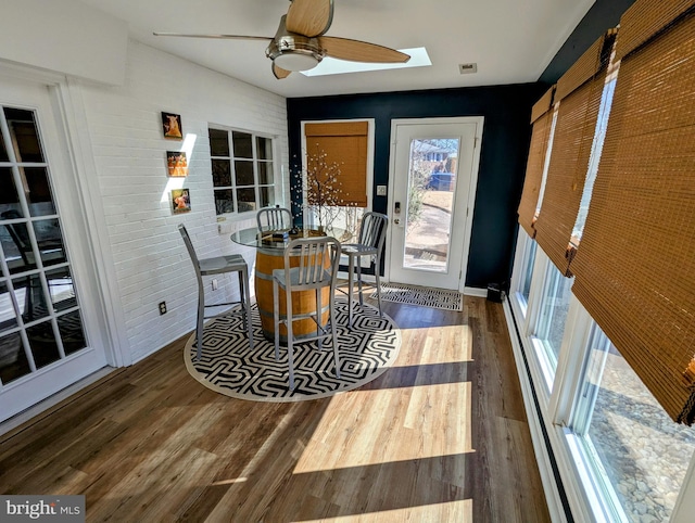 dining area featuring visible vents, dark wood finished floors, brick wall, and ceiling fan