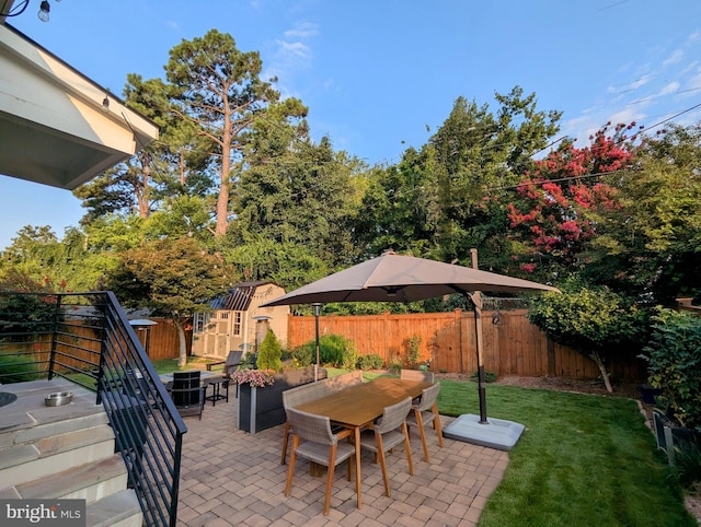 view of patio / terrace with a shed, outdoor dining space, an outdoor structure, and a fenced backyard