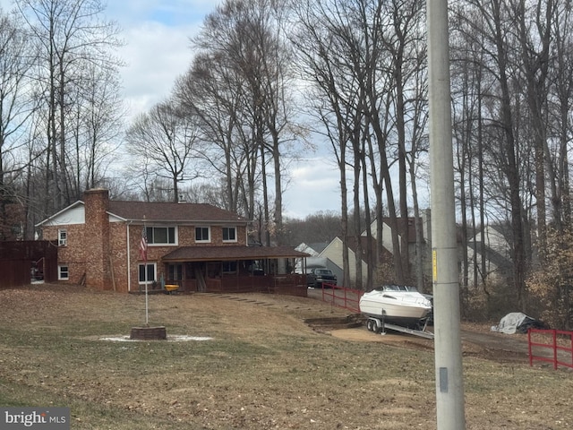 view of front of property with brick siding, a front lawn, and a chimney