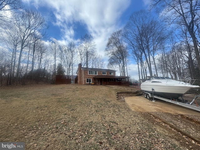 exterior space featuring brick siding, a front lawn, and a chimney