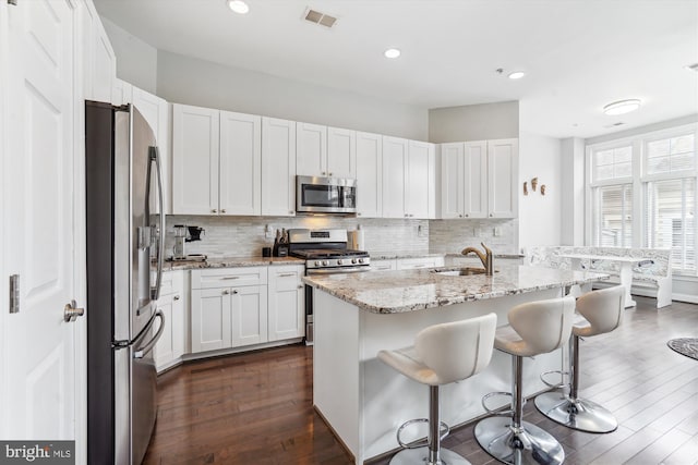 kitchen with stainless steel appliances, a sink, visible vents, and decorative backsplash