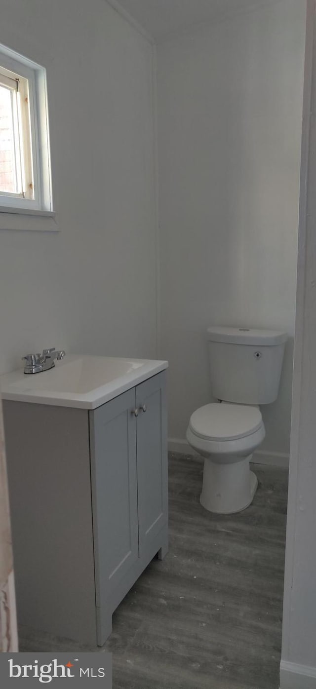 bathroom featuring toilet, baseboards, wood finished floors, and vanity