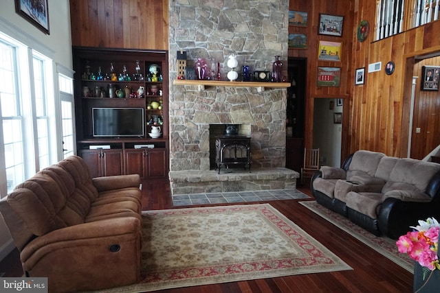 living room featuring a wood stove, wooden walls, and dark wood-style flooring