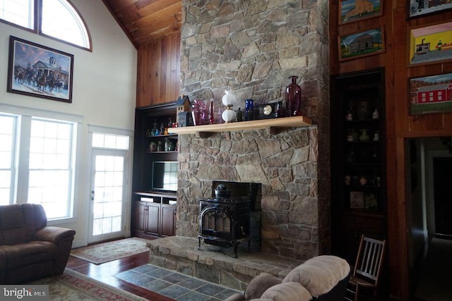 living room with built in features, wood ceiling, a wood stove, wood finished floors, and high vaulted ceiling