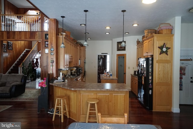 kitchen featuring a peninsula, a breakfast bar area, pendant lighting, and freestanding refrigerator