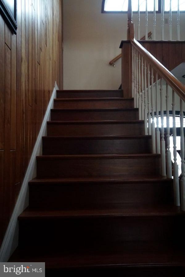 stairway featuring wood walls