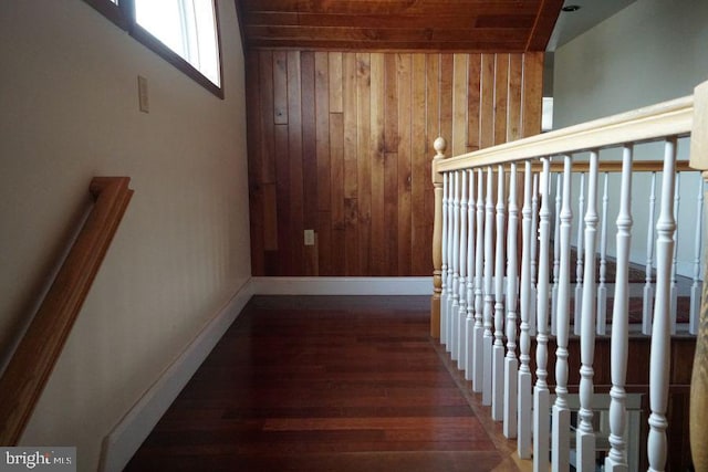 hallway with wood walls, stairway, baseboards, and dark wood-type flooring