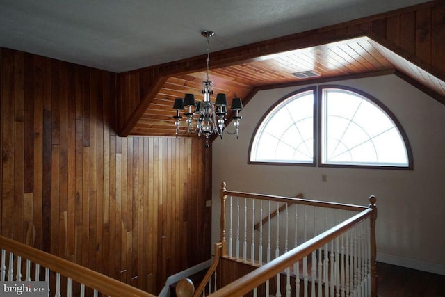 interior space with vaulted ceiling, wood walls, and an inviting chandelier