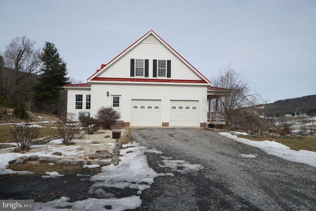 view of front of property featuring gravel driveway and an attached garage